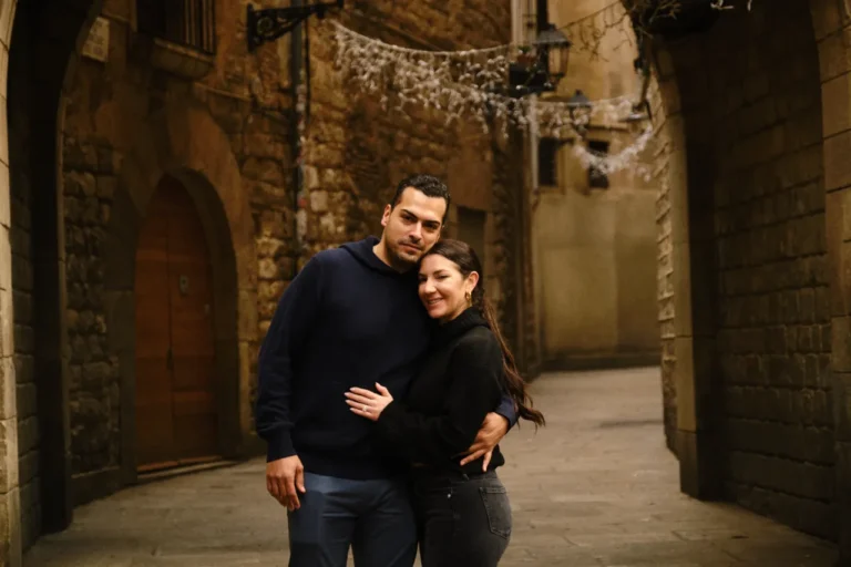 Newly engaged couple sharing a warm hug in a quiet medieval square of the Gothic Quarter.