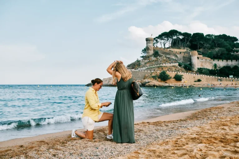 woman kneeling for a surprise marriage proposal on the scenic rocks of Tossa de Mar.