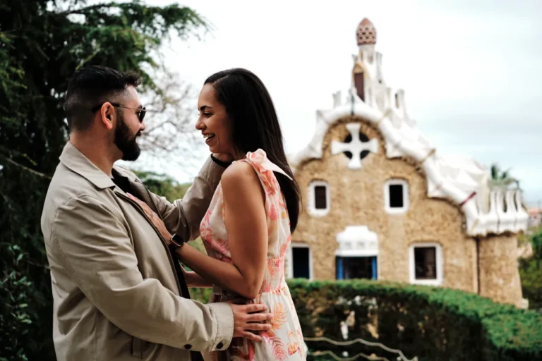 Happy couple posing in front of the colorful gingerbread gatehouses at Park Güell.