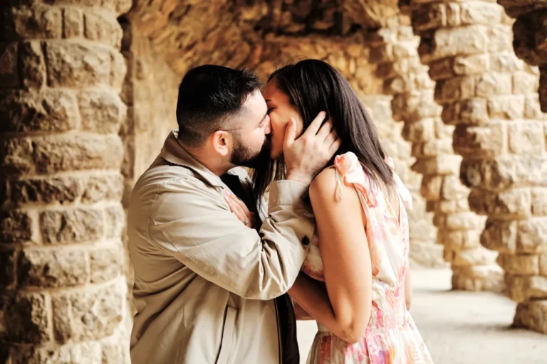 Intimate engagement kiss with the iconic Gaudí architecture in the background.