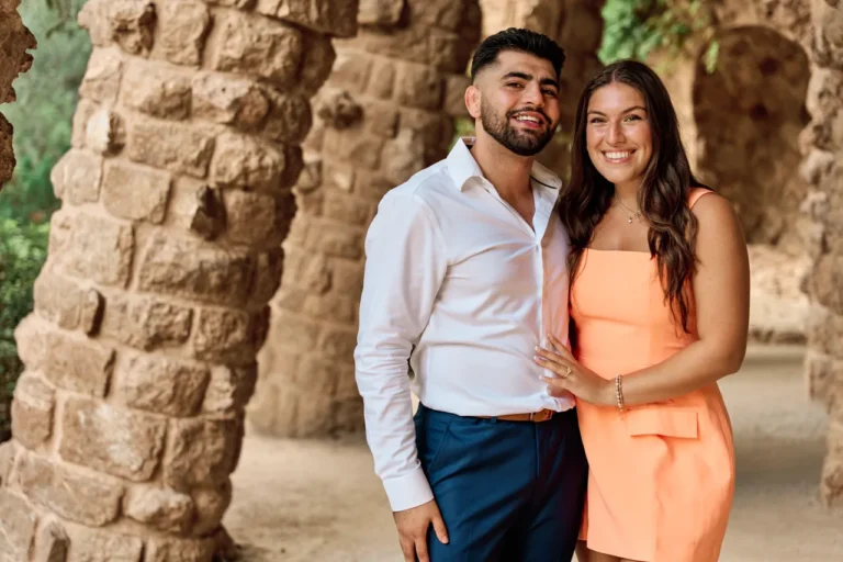 Romantic couple portrait under the stone arches of the Park Güell portico.