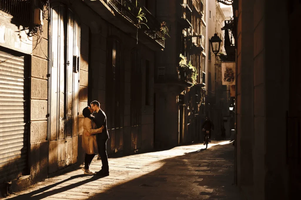 Romantic couple embrace in a sun-drenched medieval street in Barcelona.