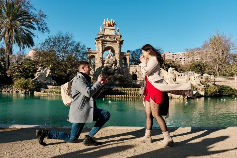 Happy couple celebrating a surprise engagement at the Parc de la Ciutadella fountain.