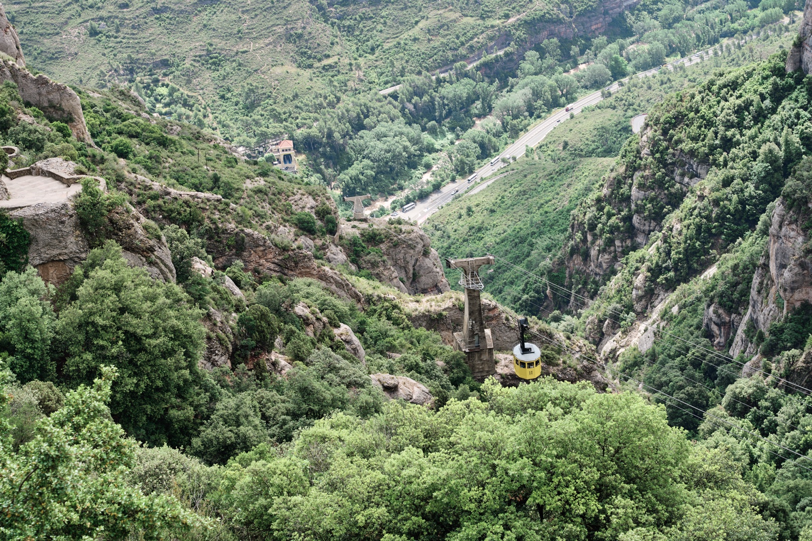 Montserrat cable car traveling through green mountain valley