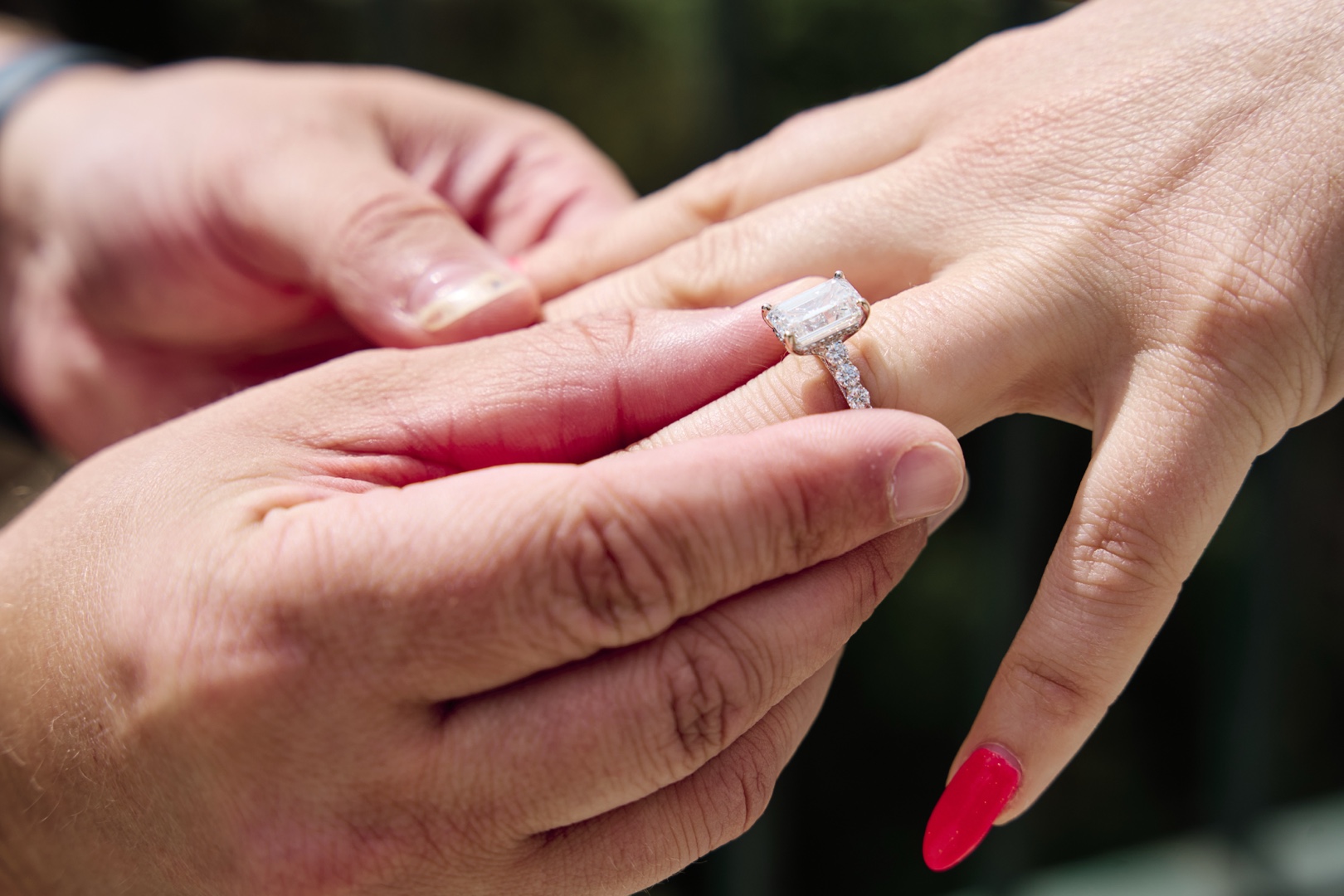 Hands putting engagement ring on finger