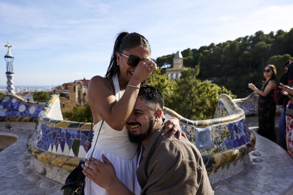 Woman covering her face in surprise and laughing moments after being proposed to at Park Güell